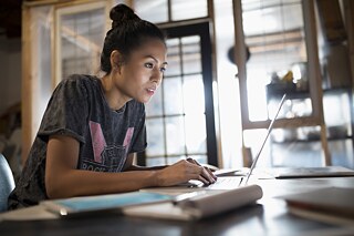 Eine junge Frau sitzt vor dem Laptop.