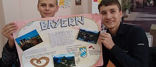 Zwei Jungen halten ein Plakat über Bayern hoch