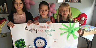 Kinder halten Plakat über Plastikmüll hoch
