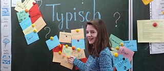 Mädchen steht an der Tafel mit Kärtchen über Deutschland und Deutsche