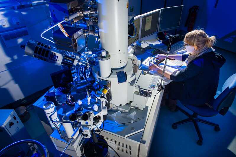 Forscherin arbeitet an einem Elektronenmikroskop