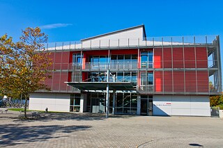 Rot-weißes, mehrstöckiges Schulgebäude vor blauem Himmel