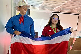 Zwei Jugendliche halten eine große Flagge von Costa Rica. 