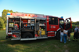 Junge Menschen besichtigen einen Feuerwehrwagen.