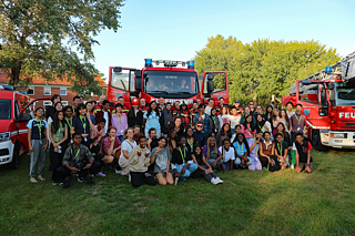 Eine größere Gruppe Jugendlicher vor einem Feuerwehrwagen