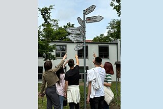 Jugendliche stehen vor Wegweisern.