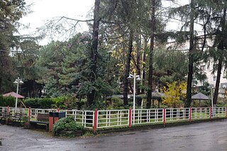 Das Bild zeigt den Zaun einer Schule in der Türkei. Die Schule umgibt ein grüner Park.