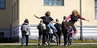 Schüler*innen springen in die Luft vor der Oulun Suomalaisen Yhteiskoulun lukio