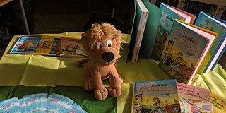 Ein Stoffhund und verschiedene deutsche Kinderbücher auf einem Tisch